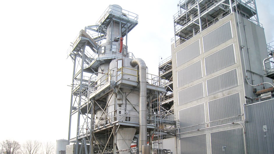 一個大型集塵裝置坐落在一個工業廠房外麵。一組金屬樓梯位於單元的外部。