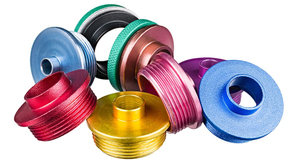 色彩鮮豔的圓形金屬部件聚集在一起，彼此靠在一起。顏色包括紅色、淺藍色、黃色、粉色、粉色和紫色金屬部分。